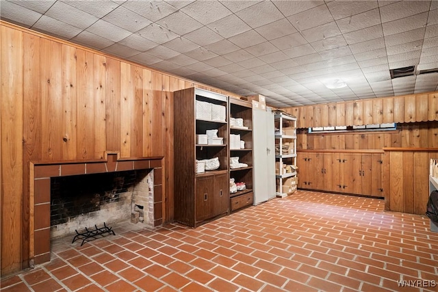 interior space with brick floor, a brick fireplace, and wood walls