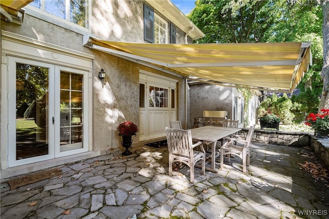 view of patio featuring french doors, outdoor dining space, exterior kitchen, and area for grilling