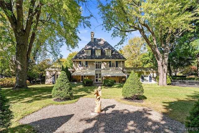 view of front of house with a front lawn, a chimney, and fence