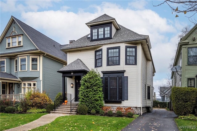 view of front of home with a shingled roof and a front yard