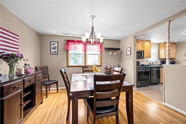 dining area featuring a chandelier, light wood-style floors, and baseboards