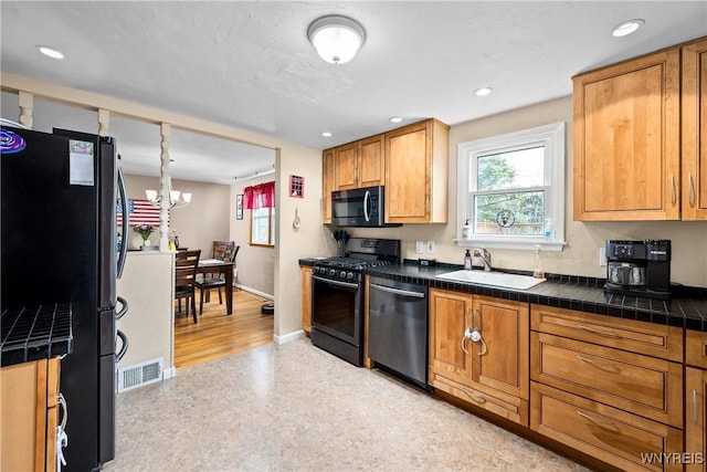 kitchen with a sink, appliances with stainless steel finishes, baseboards, a notable chandelier, and visible vents