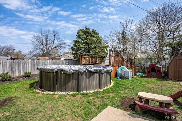 view of yard with a fenced in pool, a fenced backyard, an outdoor structure, a storage unit, and a deck