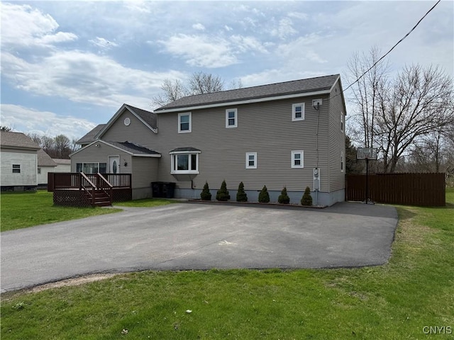rear view of house featuring a lawn, driveway, and a deck