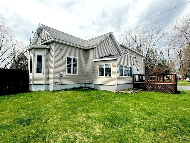 rear view of house with fence, a shingled roof, a yard, and a deck