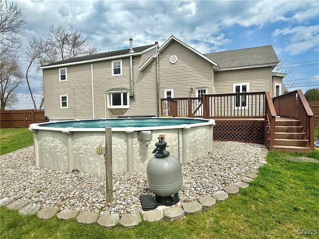 rear view of property with a wooden deck, fence, a fenced in pool, and a shingled roof