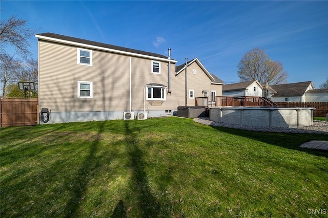 rear view of house with a fenced in pool, a lawn, and fence