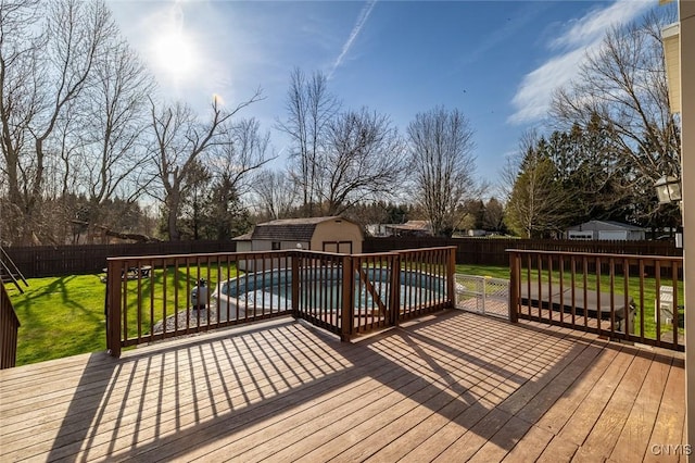 deck featuring a fenced backyard, an outbuilding, a shed, and a lawn