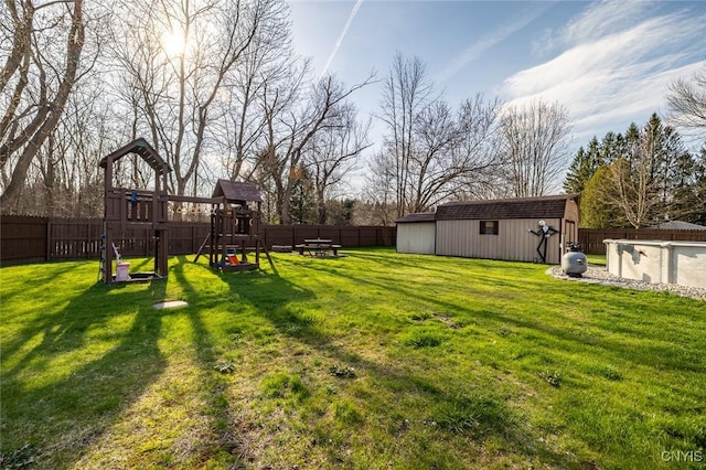view of yard featuring a fenced backyard, an outdoor structure, and a playground