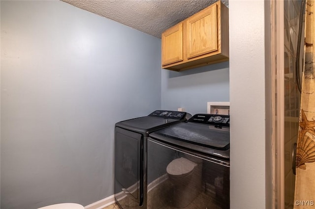 washroom with washer and dryer, baseboards, cabinet space, and a textured ceiling