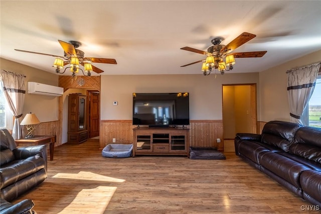 living area with a wainscoted wall, wood walls, wood finished floors, a wall mounted AC, and ceiling fan