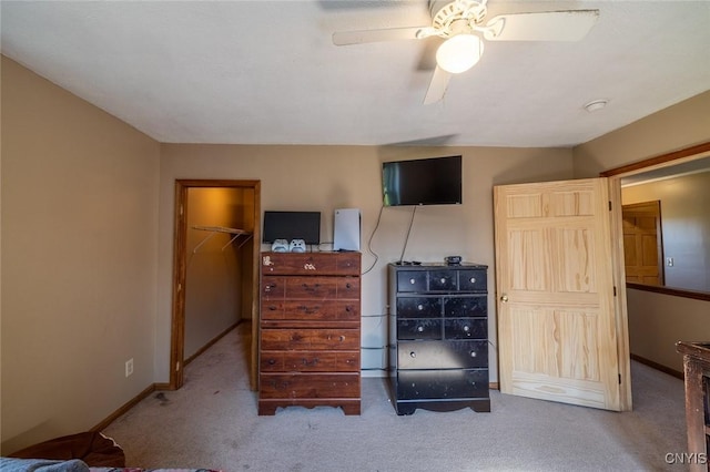 carpeted bedroom with a walk in closet, a closet, baseboards, and ceiling fan