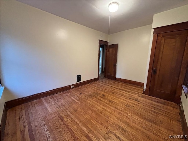 unfurnished bedroom with baseboards, wood finished floors, and a closet