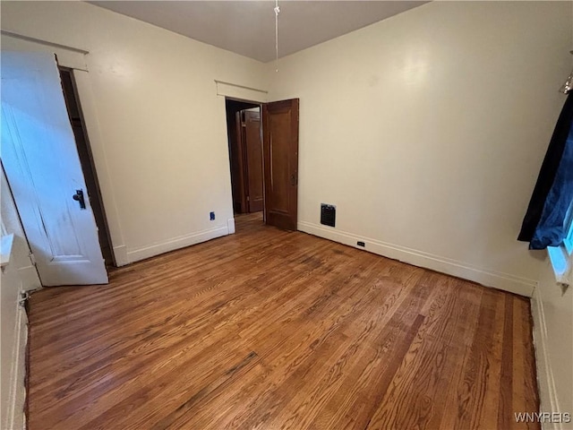 unfurnished bedroom with baseboards, wood finished floors, and visible vents