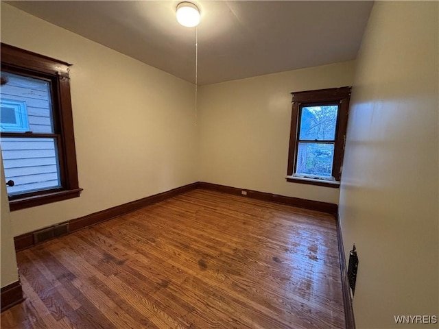 empty room with baseboards, wood finished floors, and visible vents