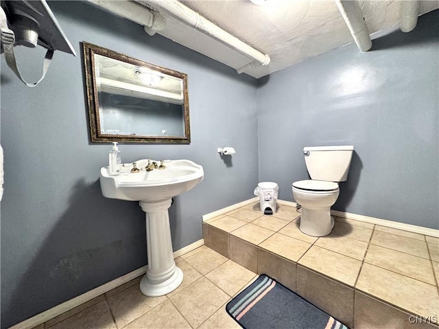 half bathroom featuring tile patterned floors, baseboards, and toilet