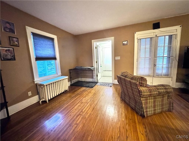 living room with radiator heating unit, baseboards, and wood finished floors