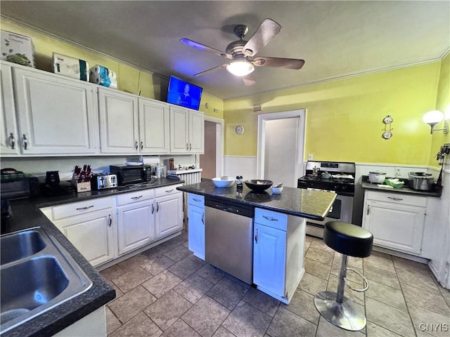 kitchen with a ceiling fan, a center island, dark countertops, white cabinetry, and appliances with stainless steel finishes