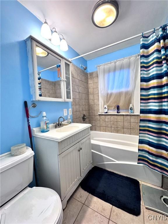 full bathroom with shower / tub combo with curtain, tile patterned floors, vanity, and toilet