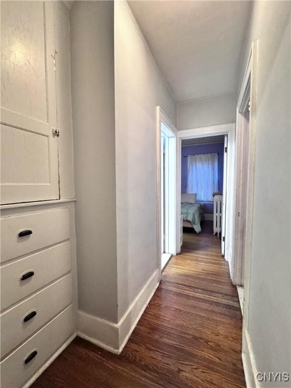 corridor featuring baseboards and dark wood-style flooring