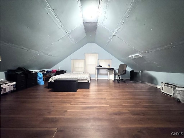 bedroom featuring hardwood / wood-style flooring, baseboards, vaulted ceiling, and a wall mounted air conditioner