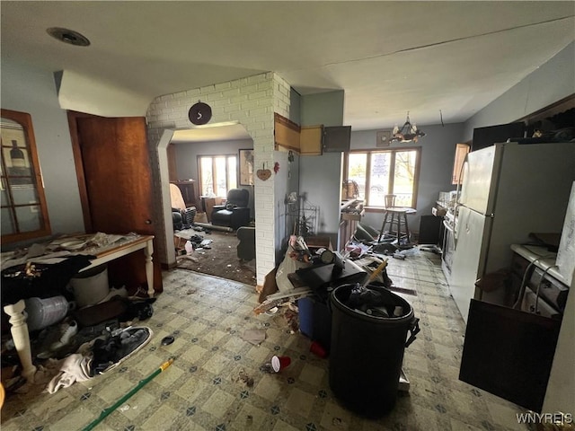 kitchen featuring arched walkways, a wealth of natural light, a notable chandelier, and lofted ceiling