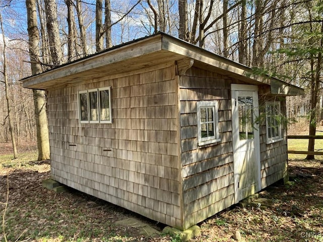view of outdoor structure featuring fence and an outbuilding