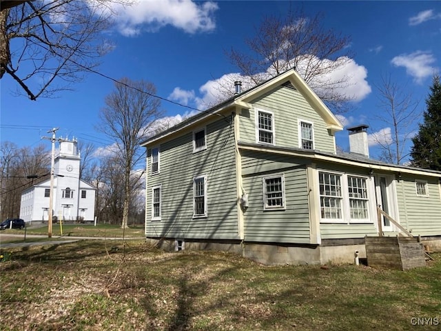 view of side of property featuring entry steps and a chimney