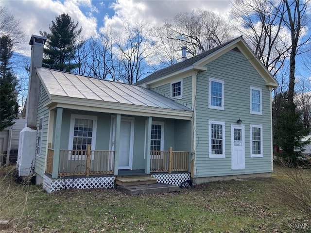 back of property with a lawn, a chimney, and covered porch