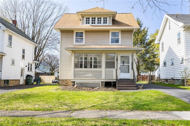 traditional style home featuring a shingled roof, a front lawn, and a sunroom