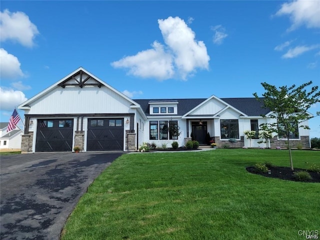view of front of home with driveway, stone siding, a shingled roof, a front lawn, and a garage