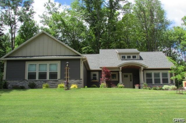craftsman inspired home featuring board and batten siding, a front lawn, and stone siding