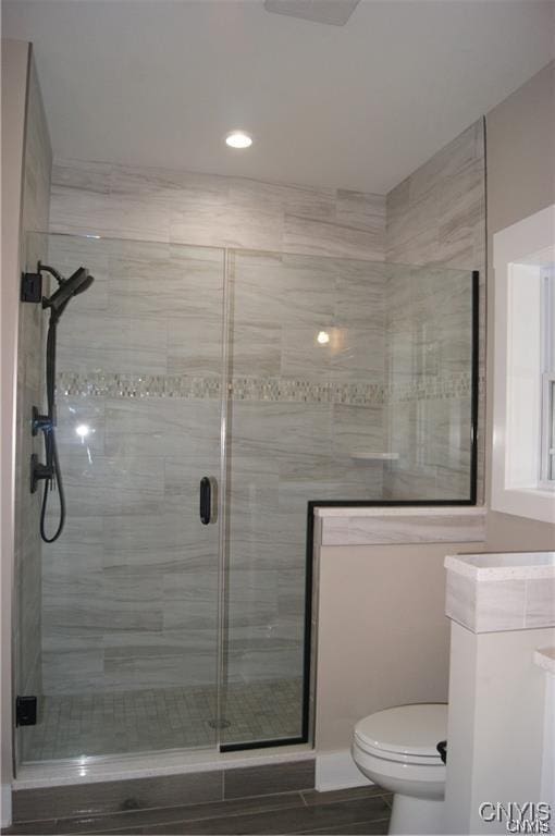 full bath featuring toilet, recessed lighting, and a shower stall