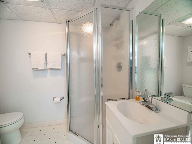 full bath featuring tile patterned floors, a stall shower, toilet, and a paneled ceiling