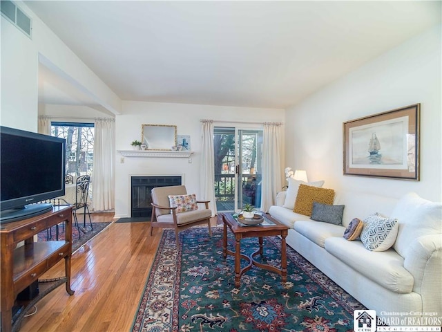 living area featuring visible vents, wood finished floors, and a fireplace