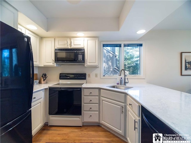 kitchen with recessed lighting, a sink, black appliances, light countertops, and white cabinets