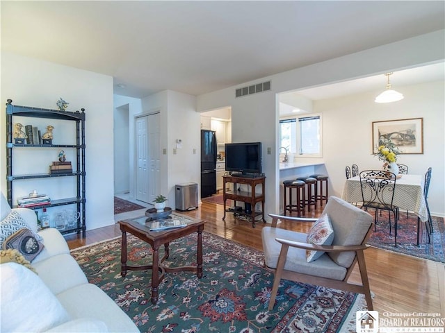 living area with visible vents and wood finished floors