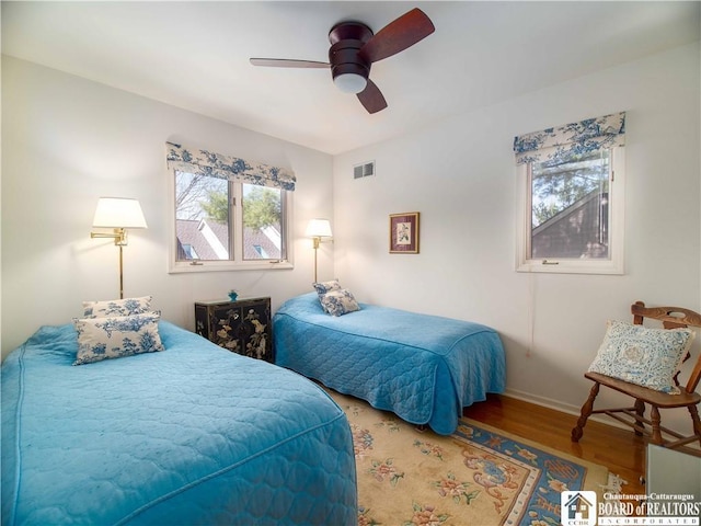bedroom with baseboards, visible vents, wood finished floors, and ceiling fan