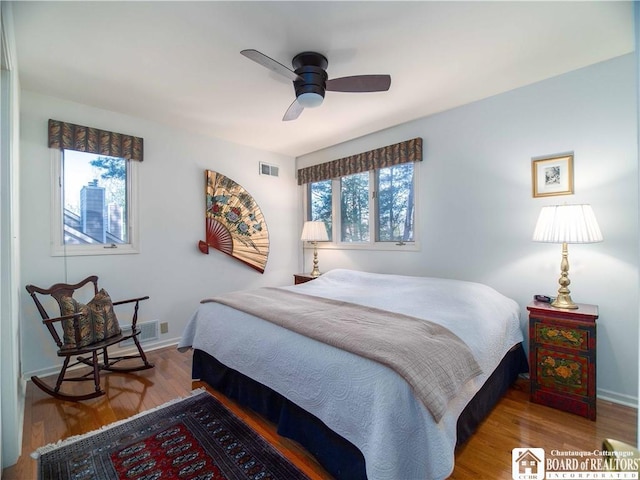 bedroom with wood finished floors, a ceiling fan, visible vents, and baseboards