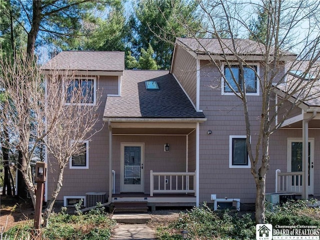 view of front of home with central AC unit and roof with shingles