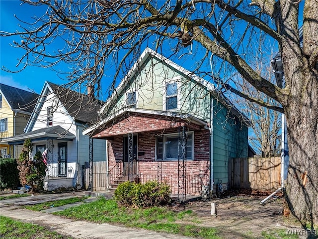 view of front of property with a chimney, brick siding, and fence