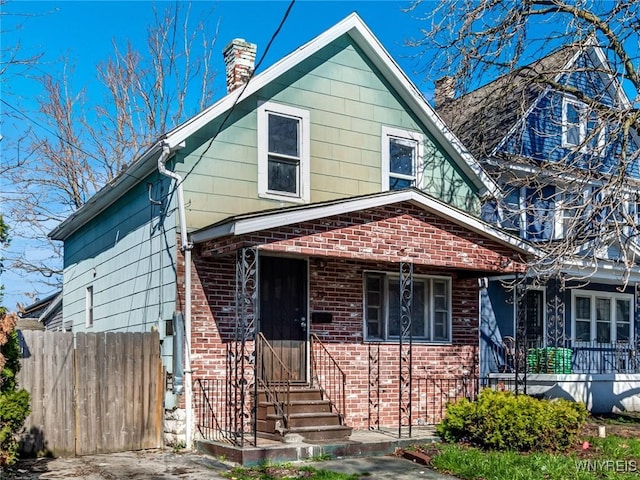 view of front of property featuring a chimney, brick siding, fence, and entry steps