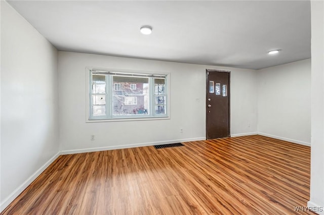 foyer with baseboards, visible vents, and wood finished floors