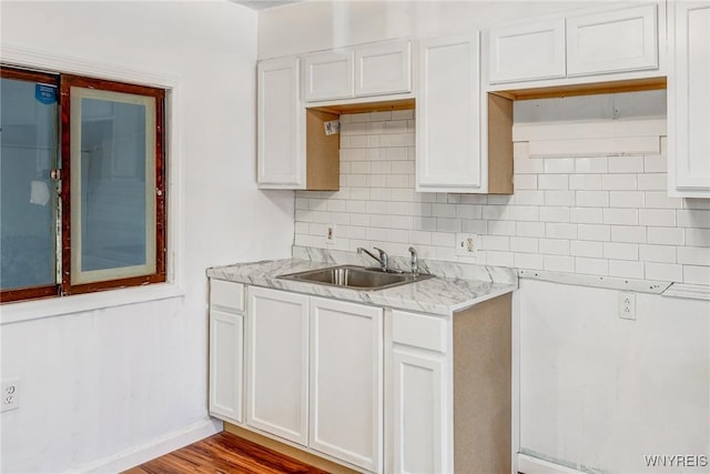 kitchen featuring a sink, white cabinets, decorative backsplash, and baseboards