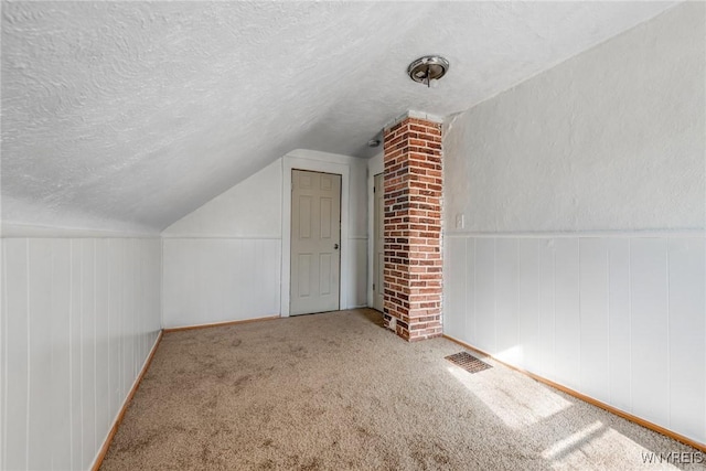 bonus room with a textured ceiling, lofted ceiling, and carpet floors