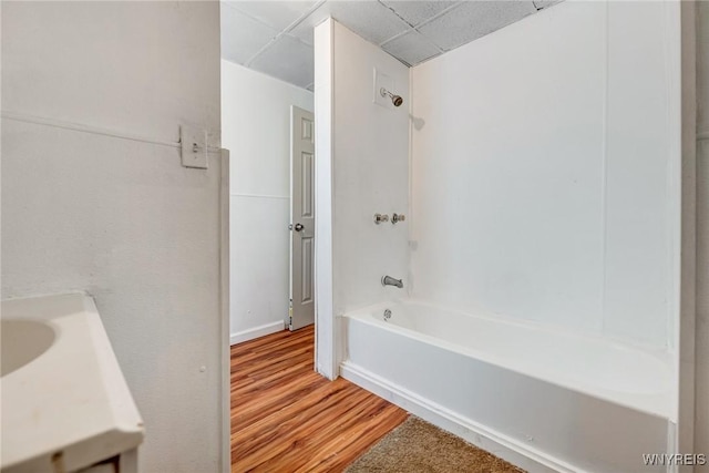bathroom with vanity, washtub / shower combination, a drop ceiling, and wood finished floors