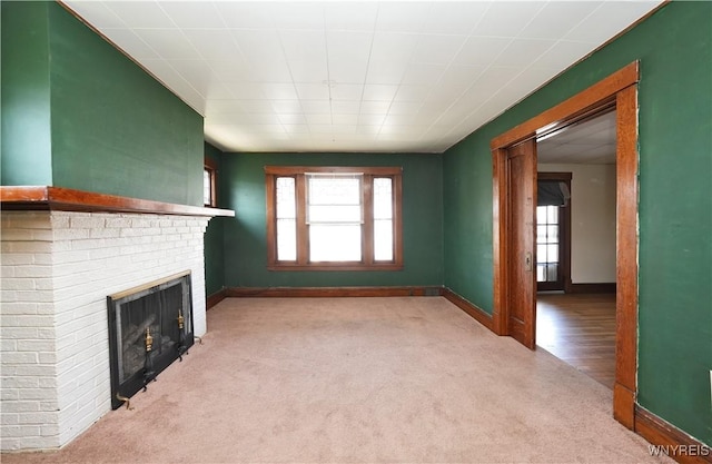 unfurnished living room with a fireplace, a wealth of natural light, carpet flooring, and baseboards