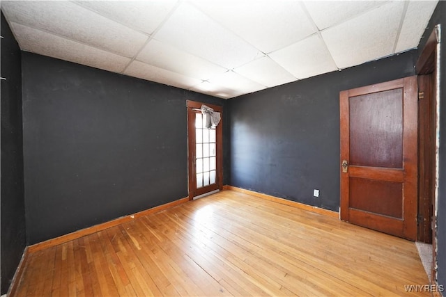 unfurnished room with a paneled ceiling, hardwood / wood-style flooring, and baseboards