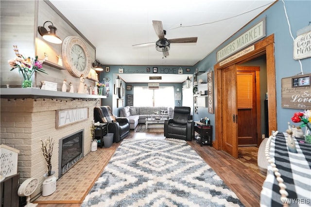living area featuring wood finished floors, ceiling fan, and a fireplace