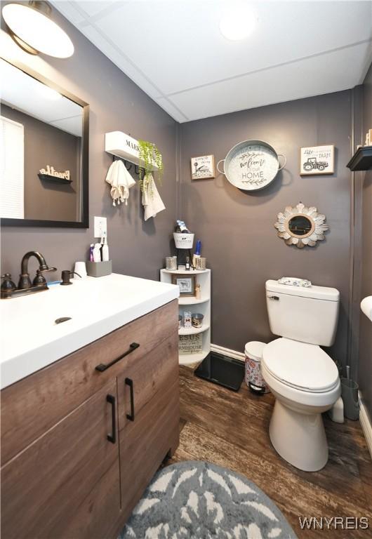 bathroom with wood finished floors, toilet, vanity, and baseboards